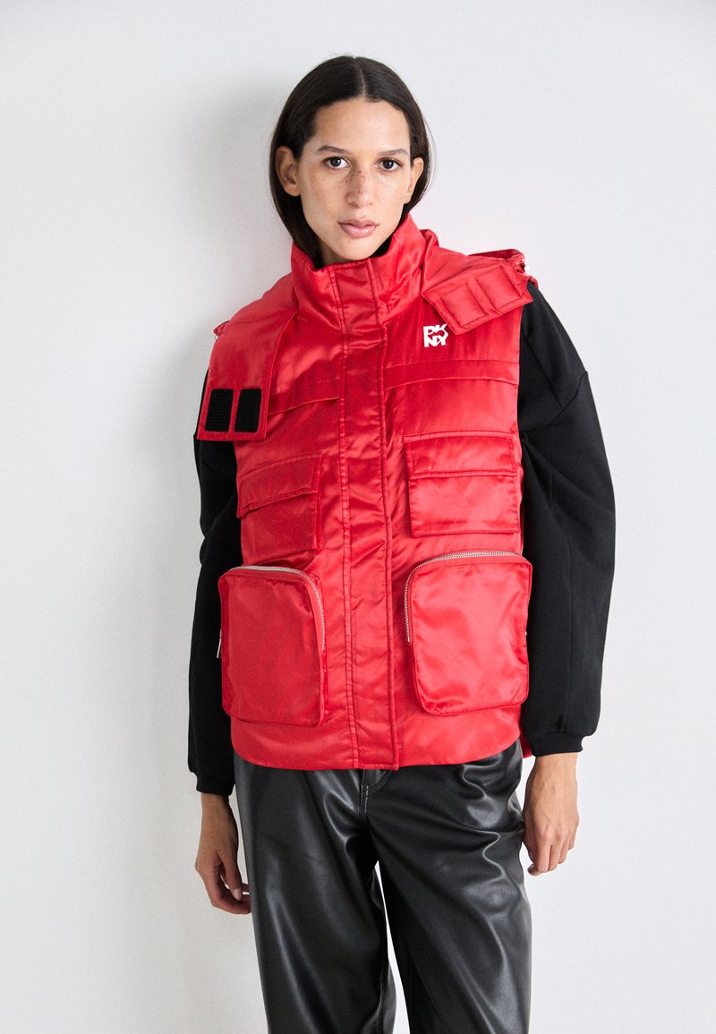 Rode gewatteerde vest met hoge kraag, meerdere voorzakken en ritssluitingen, gemaakt van glanzende stof, met een logo-detail op de borst.