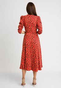 Czerwona sukienka midi w czarno-różowy wzór lamparta, z bufiastymi rękawami i szwami w talii, uszyta z gładkiego materiału z lejącą się spódnicą.