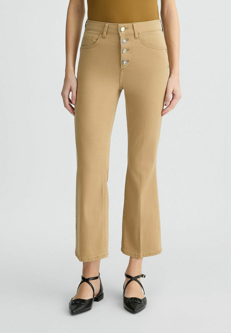 Beige flare jeans met een hoge taille en vijfknopen sluiting, voorzien van riemlussen en voorzakken, gemaakt van een katoenmix.