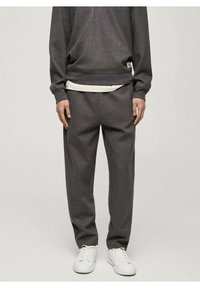 Sweat-shirt gris et pantalon assorti en tissu doux, avec une coupe décontractée et un t-shirt blanc en dessous. Porté avec des baskets blanches.