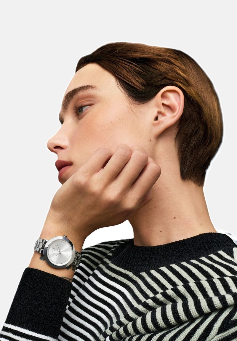 Profiilipilt inimesest, kellel on lühikesed pruunid juuksed, seljas must-valge triibuline suhtel ja vasakul randmel hõbedane käekell.