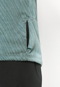 Light blue shirt featuring a diagonal striped texture, half-zip side pocket with black trim, and a fitted design.