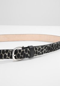 Leopard print belt with a silver metal buckle, black and gray color scheme, smooth texture, and a plain tan interior.