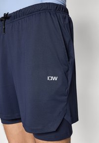 Marinefarbene Sportshorts aus strukturiertem Stoff mit elastischem Bund und Seitentaschen. "ICIW"-Logo in Weiß auf dem linken Bein.