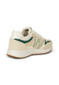 Sneaker beige clair avec des accents verts, matériaux en mesh et en daim, design perforé, semelle en caoutchouc et lacets plats.