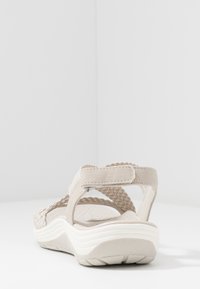 Beige geflochtene Sandalen mit verstellbaren Riemen, gepolsterter Innensohle und einer weißen, strukturierten Sohle. Sie verfügen über eine abgerundete Rückseite und einen sicheren Sitz.