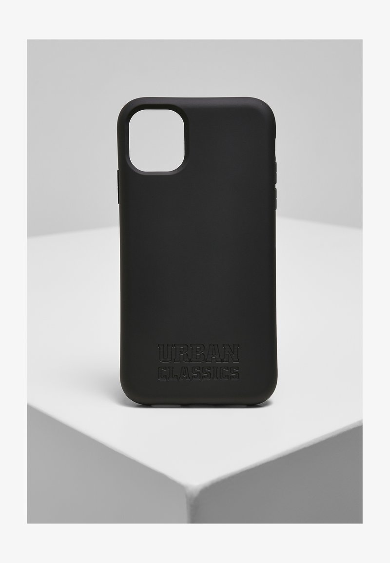 Svart silikontelefonfodral med en matt yta, som har ett utskärning för kameran och ett präglat "URBAN CLASSICS"-logotyp på den nedersta kanten.