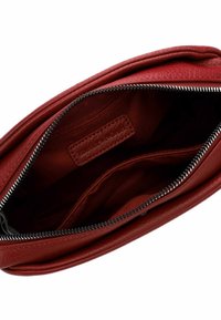 Interior de un bolso de cuero rojo, con una textura suave, cierre de cremallera y múltiples compartimentos para organización.