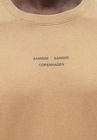 T-shirt bege de algodão com gola redonda canelada e texto do logótipo impresso "SAM SøE SAM SøE COPENHAGEN" em preto na parte da frente.