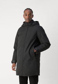 Schwarze wasserdichte Parka mit Kapuze, langen Ärmeln und seitlichen Taschen. Verfügt über einen Reißverschluss vorne und verstellbare Verschlüsse an den Manschetten.