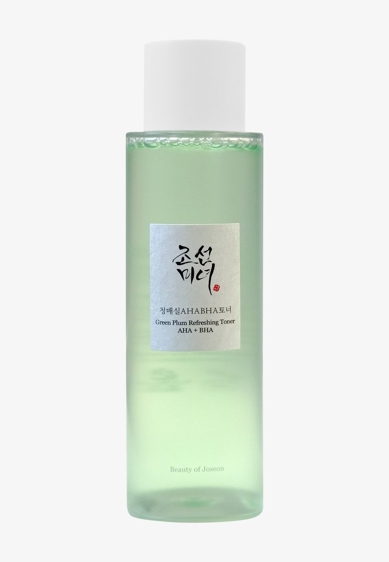 Bottiglia trasparente di tonalità verde con un tappo bianco. L'etichetta presenta testo nero su sfondo bianco, che indica "Tonico Rinfrescante al Prugno Verde."