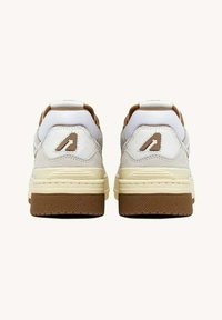 Sneaker bianche con tacco imbottito, accenti beige, suola in gomma e dettaglio del logo sul retro. Materiale testurizzato e collo imbottito.