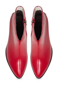 Bottes mi-mollet en cuir rouge avec un bout pointu, une fermeture éclair, et une texture lisse, avec des semelles noires contrastantes.