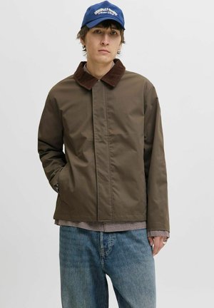 Brown insulated jacket with a corduroy collar, featuring a zip and button closure, worn over a checked shirt, and paired with light blue jeans.