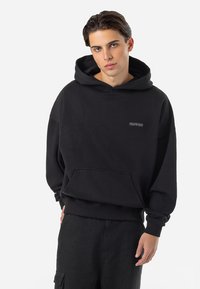 Sort hættetrøje lavet af blødt stof, med en frontlomme og et lille, diskret logo. Oversized design med ribbede manchetter.
