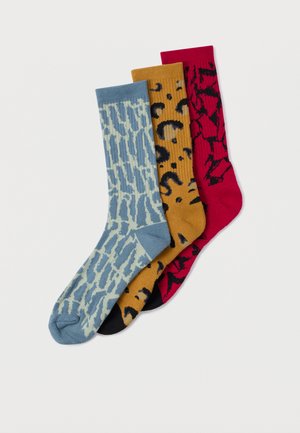 Tri páry ponožiek: modré s vlnovým vzorom, horčicové s leopardím potlačou a červené s grafickým dizajnom. Všetky sú rebrované a s dĺžkou po stred lýtok.