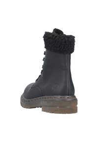 Schwarze Leder-Ankle-Boots mit einem fusseligen schwarzen Saum, Schnürdesign, strapazierfähiger Gummisohle und sichtbaren Nähten entlang der Kante.