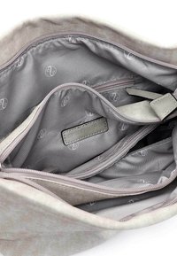 Intérieur de sac en tissu gris clair avec doublure à motifs, plusieurs poches zippées et une étiquette en cuir à texture lisse.