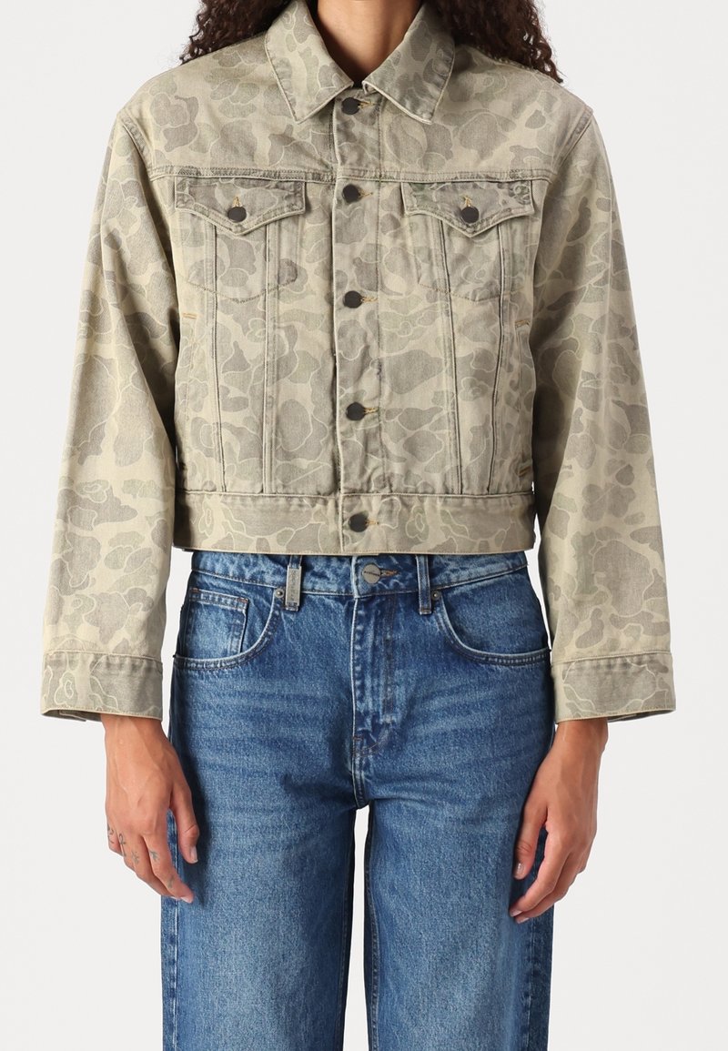 Afklippet denimjakke i en lys beige farve med et subtilt mønster, der har to brystlommer, knaplukning og manchetter på ærmerne.