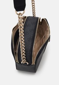 Bolso bandolera negro con cadena dorada, que cuenta con dos compartimentos con cremallera. Exterior texturizado con un patrón sutil y forro beige.