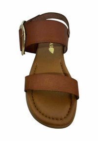 Sandalia de cuero marrón con dos correas anchas y una hebilla circular de plata. Textura suave y suela plana, resaltada por costuras visibles.