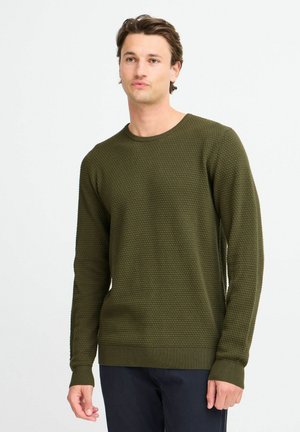 Olivenfarget strikket genser med en teksturert, hevet mønster, ribbestrikkede mansjetter og kant. Fitted design med rund hals og hele ermer.