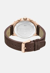 Orologio con cassa in acciaio inox rose gold, cinturino in pelle marrone texturizzato, incisione "POLICE" sul retro e sulla fibbia, resistente all'acqua fino a 5 ATM.