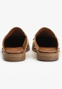 Bakvy av bruna lädersandaler med en öppen design, vadderade innersulor och låga träklackar med horisontella ränder.