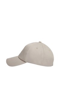 Gorra de béisbol de algodón beige con visera curva y orificios de ventilación, mostrada desde un ángulo lateral sobre fondo blanco.