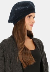 Ciemnogranatowy beret o teksturowanym wzorze, ozdobiony małymi błyszczącymi cekinami, w oversize'owym kształcie, z dopasowanym ściągaczem.