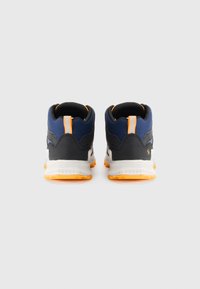 Sneakers z czarną i granatową cholewką, pomarańczowymi akcentami, teksturowanym materiałem i białą podeszwą. Posiadają pętelkę na pięcie oraz wzorzystą gumową podeszwę.