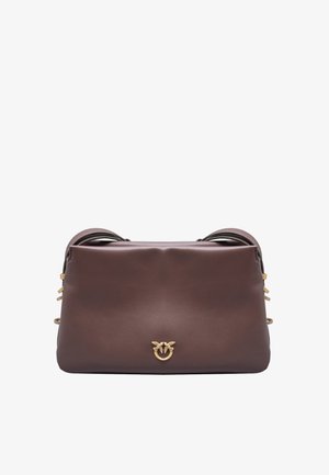 Bolso de mano de cuero marrón con una textura suave, que presenta un emblema dorado, asas dobles en la parte superior y detalles decorativos en los laterales.