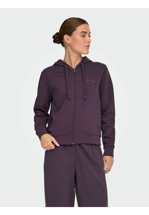 Ljubičasta zip-up dukserica od mekog materijala, koja ima kapuljaču, praktične vezice i prednji džep. Mali logo otisnut na lijevoj strani grudi.