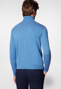 Jasnoniebieski sweter, miękki materiał dzianinowy, wysoki kołnierz, dopasowany krój, ściągacze u rękawów i u dołu, gładki design, odpowiedni na co dzień.