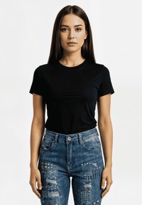 Camiseta negra de manga corta combinada con jeans de denim azul que presentan diversas texturas y adornos. Diseño simple y ajustado.