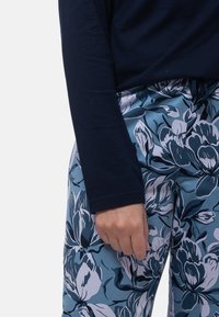 T-paita pitkällä hihaisella navy-sinisenä, yhdistettynä sinivalkoisiin kukkakuosisiin housuihin, joissa on nyörikiinnitys vyötäröllä ja pehmeä kangas.