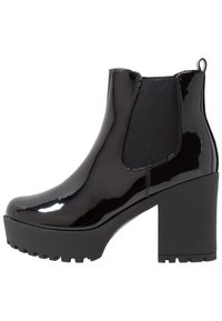 Lesklá černá kotníková bota s masivním vysokým podpatkem, elastickými bočními panely a silnou platformou, vybavená poutkem vzadu.