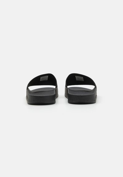 Black slide sandals with a textured rubber sole and wide straps, featuring an open back design for easy wear and ventilation.