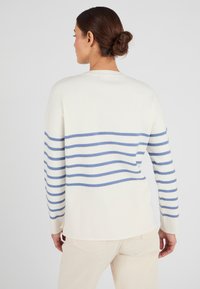 Crème trui met blauwe horizontale strepen, zachte stof, lange mouwen en een lichte high-low zoom. Eenvoudig ontwerp in een losse pasvorm.