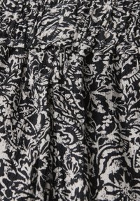 Schwarzer und weißer Stoff mit floralen Mustern und komplizierten, schwingenden Designs. Strukturierter Webstuhl mit gerafften Details. Geeignet für Kleidung oder Wohnkultur.