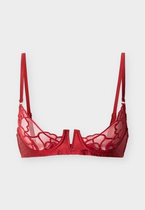 Reggiseno rosso con ferretto con coppe in pizzo floreale trasparente e spalline regolabili su uno sfondo chiaro uniforme.