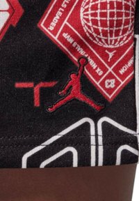Shorts neri con stampe grafiche rosse, incluso il logo Jumpman. Testo e forme contornati in bianco. Tessuto morbido e strutturato.