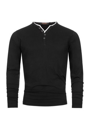 Musta pitkähiha paita, joka on valmistettu puuvillasta ja jossa on valkoinen kontrastikaulus, henley-kaula-aukko ja kolmen napin nappilista. Sileä pinta.