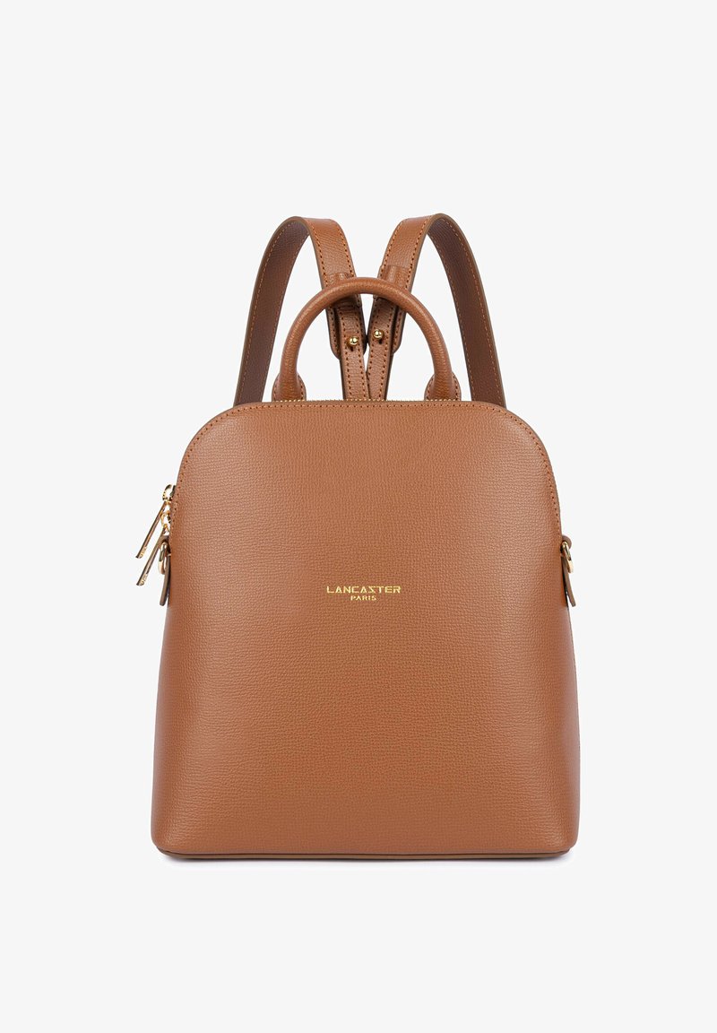 Sac à dos en cuir marron avec deux bretelles, une petite poignée, des fermetures éclair dorées et le logo "Lancaster Paris" à l'avant.