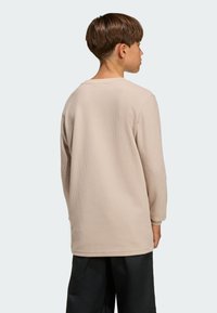 Bež dolgo rokavna srajca iz teksturirane tkanine, z okrolim izrezom in običajnim krojem. Hrbtna stran prikazuje rokave do sredine roke ter minimalne šive.
