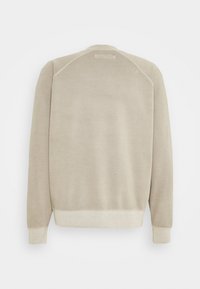 Beżowy sweatshirt z okrągłym dekoltem, rękawami raglanowymi i ściągaczami. Miękka tekstura z subtelnym tonalnym szwem z tyłu.
