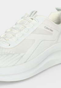 Бял маратонка Calvin Klein с текстилна материя, дизайн с връзки и дебела омекотена подметка.