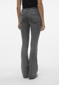 Grå utsvängda jeans med hög midja, femficksdesign och en blekt tvätt. Lätt stretch i materialet, synliga sömnadsdetaljer.