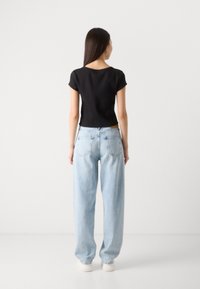 Black cropped short-sleeve top paired with light blue high-waisted wide-leg jeans, both featuring minimalistic design and soft textures.