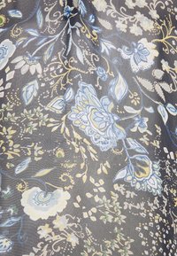 Tessuto grigio con intricati motivi floreali in blu, giallo e verde, con foglie dettagliate e vortici che attraversano tutto il design.